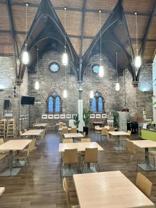 Inside a cafe with high vaulted ceiling and lots of tables and chairs